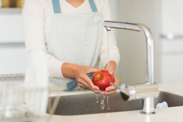 istock Housewife washing apple with water 1146433565