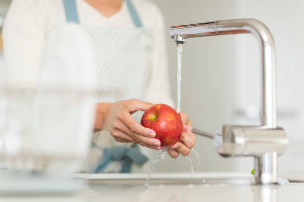 istock Housewife washing apple with water 1146433566