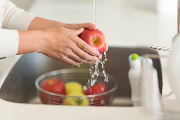 istock Housewife washing apple with water 1146433572