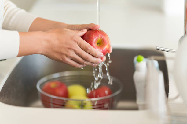 Housewife washing apple with water stock photo