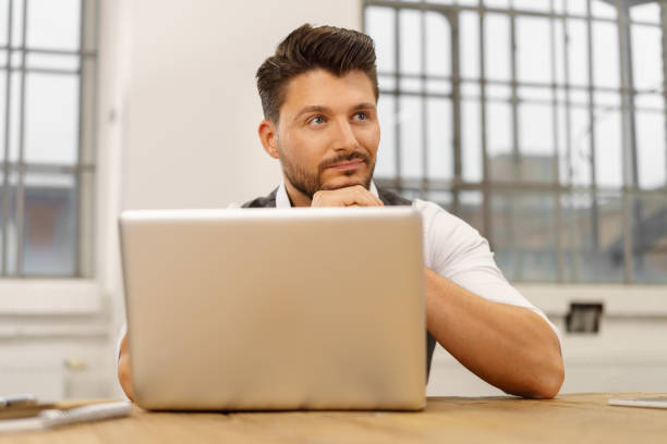 istock Young thoughtful man sitting in front of laptop 1146437419