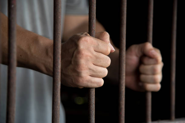 istock Close-Up Of Man Holding Prison Bars 1146438056