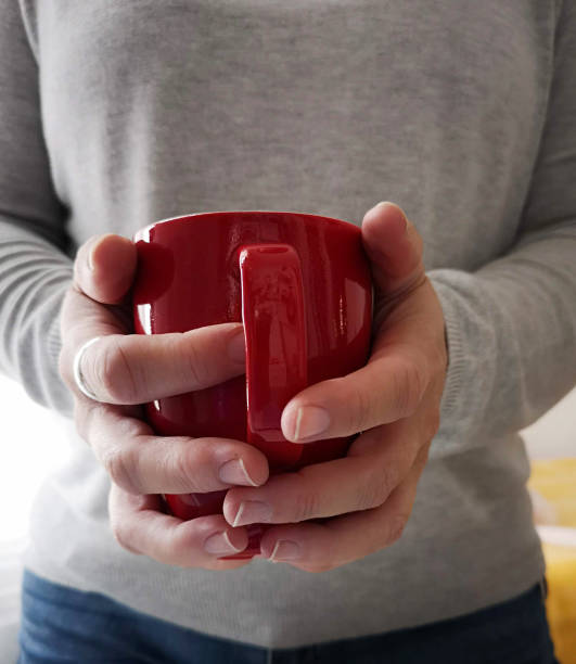 istock woman's hands holding a red cup of tea 1146438333