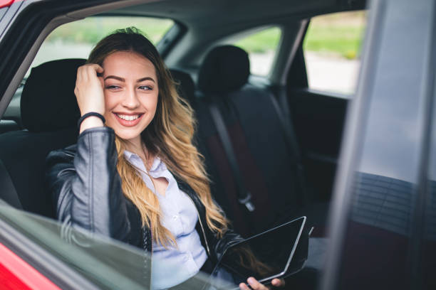 istock Smiling woman sitting in a car with tablet computer 1146438816