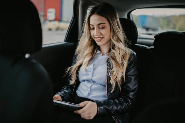 istock Smiling woman sitting in a car with tablet computer 1146438840