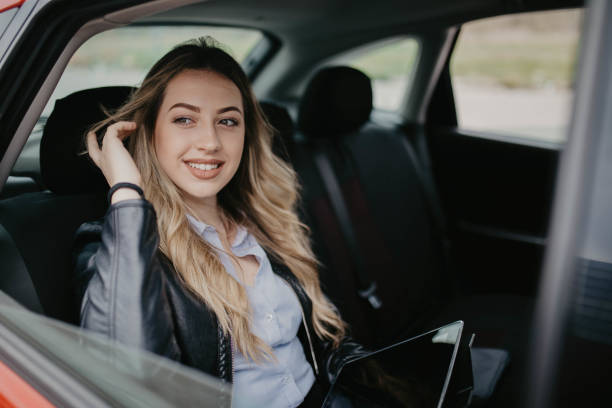 istock Smiling woman sitting in a car with tablet computer 1146438884