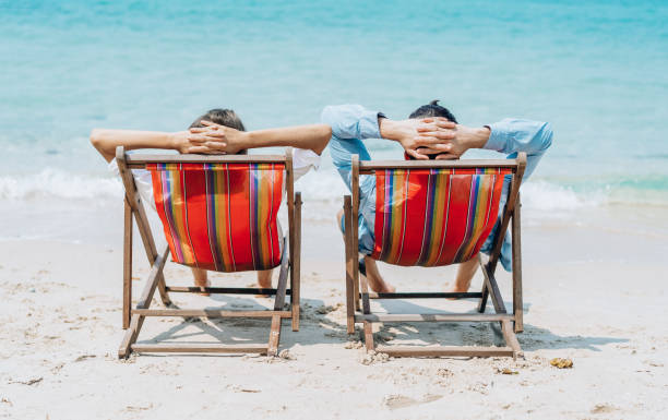 istock Happy couple having a romantic moment whilst sitting on deck chairs a blue sky on a beach, enjoying summer holidays. 1146442032