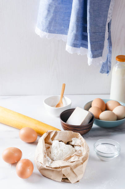 istock Vertical shot.Different components for baking.Flour, eggs, milk, yeast on the kitchen table and an apron hanging on the wall.Morning in the  kitchen 1146442073