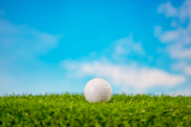 Golfer at golf ball view from inside the hole of cup in the green golf club play and lens flare on sun set evening time gold sky background.