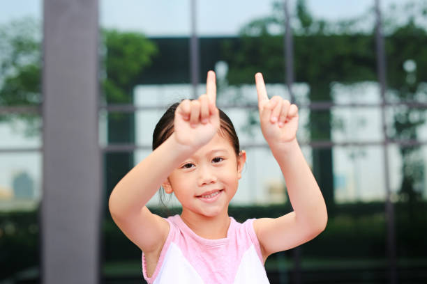 istock Asian little girl posture pointing her forefinger up with little smile. 1146445837