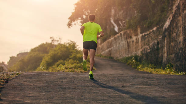 istock Man jogging on a downhill / uphill in suburb mountain road. 1146446283