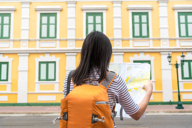 istock Rear View Of Backpacker Reading Map While Standing On Street In City 1146448358