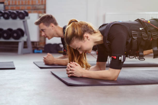 Woman exercises in gym on yoga mat besides man stock photo