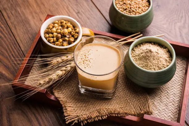 Sattu sharbat is a cooling sweet drink made in summer with roasted black chickpea flour, barley, suger, salt & water. served in a glass. selective focus