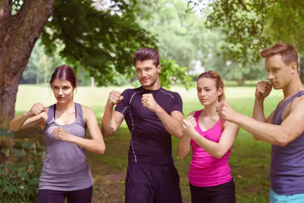 Athletes stand together in a fighting stance with fists at the ready while out on a forest clearing in