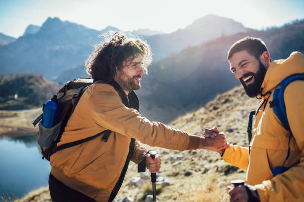 istock Helping hand - hiker man getting help on hike happy overcoming obstacle. 1146453917
