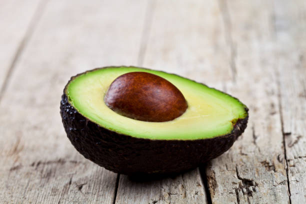 istock Fresh organic avocado half on old wooden table background. 1146456519