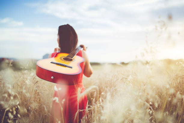 istock Woman walking through the wheat field with guitar on back. 1146456569