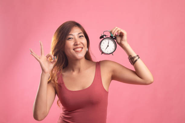 istock Young Asian woman show OK with a clock. 1146457189