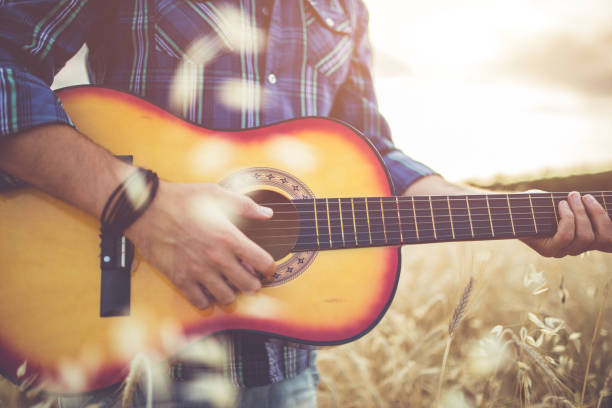 istock Man standing in wheat field and playing guitar. 1146457248