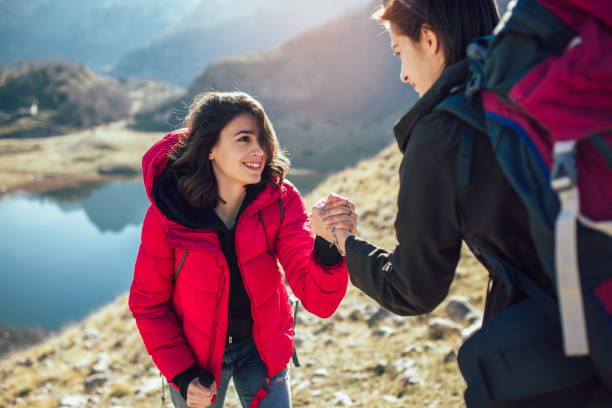 istock Helping hand - hiker woman getting help on hike happy overcoming obstacle. 1146457425