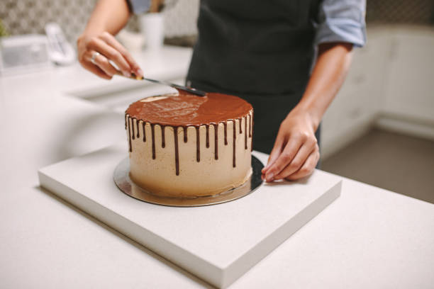 istock Confectioner decorates a cake with liquid chocolate 1146457712