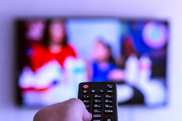 istock Remote control in hand aimed at the TV on. 1146458669
