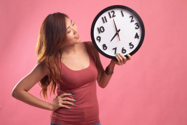 istock Young Asian woman with a clock. 1146460271