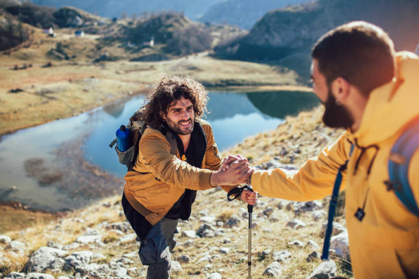 istock Helping hand - hiker man getting help on hike happy overcoming obstacle. 1146460374
