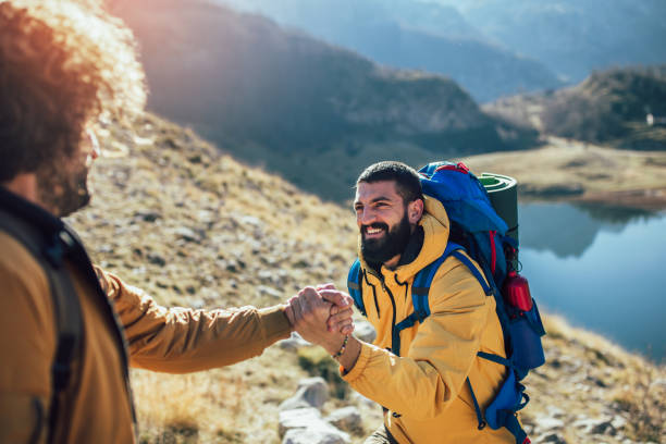 istock Helping hand - hiker man getting help on hike happy overcoming obstacle. 1146460696