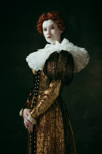 Medieval young woman as a duchess Having doubts. Medieval redhead young woman in golden vintage clothing as a duchess standing crossing hands on dark green background. Concept of comparison of eras, modernity and renaissance. duchess photos stock pictures, royalty-free photos & images