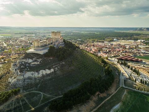 Aerial view of the famous castle of Peñafiel in Valladolid at dusk, with the old village and wine cellars in the background.