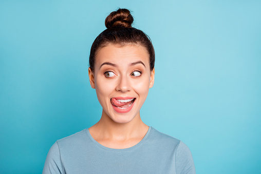 Close up photo beautiful amazing she her lady look side empty space licking tongue upper lip crazy silly mischief carefree mood giggling wear casual sweater pullover isolated blue bright background.