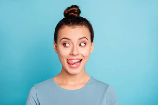 Close up photo beautiful amazing she her lady look side empty space licking tongue upper lip crazy silly mischief carefree mood giggling wear casual sweater pullover isolated blue bright background.