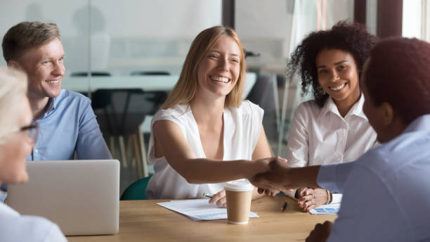 istock Happy caucasian manager and african client handshaking at group meeting 1146468350