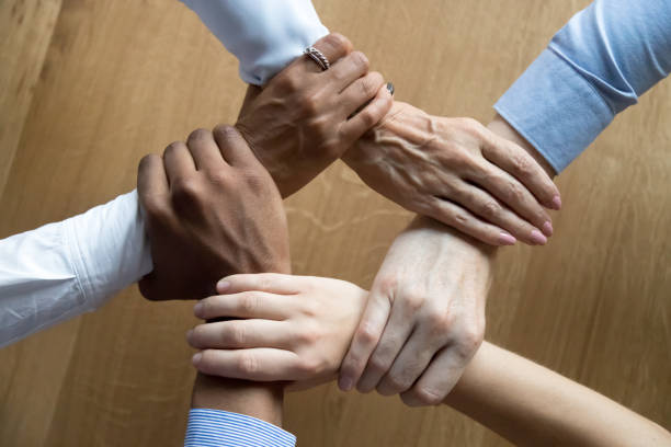 istock Diverse business people team grasping hands, close up top view 1146468357