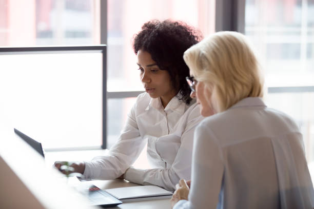 serious diverse young and old businesswomen work together on laptop - leadership business women senior adult imagens e fotografias de stock