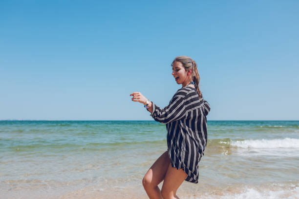 Young, beautiful, attractive, happy woman dancing on the beach, with sea background, Albena, Bulgaria.