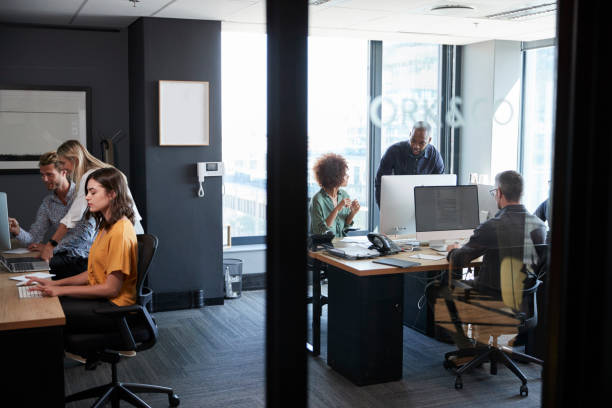 istock Young creative team working together at computers in a casual office, seen through glass wall 1146471489