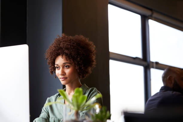 istock Millennial black female creative sitting at a desk in an office using a computer, close up 1146471541