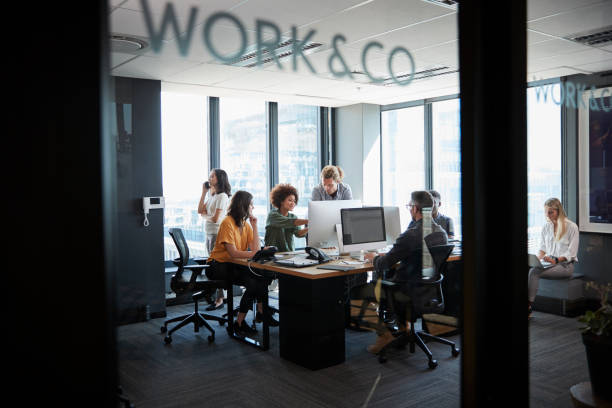 istock Creative business team working in a casual office, seen through glass wall with text on it 1146471632
