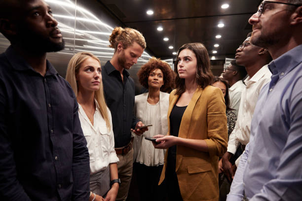 Work colleagues stand waiting together in an elevator at their office Work colleagues stand waiting together in an elevator at their office busy stock pictures, royalty-free photos & images