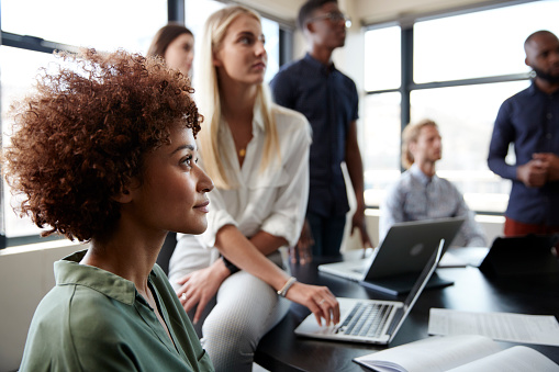 Close up of creative business colleagues listening to an informal presentation in a meeting room