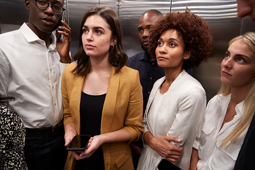 Work colleagues standing in an elevator at their office, close up