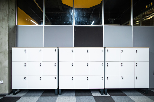 Closed lockers with keys in modern office space, no people