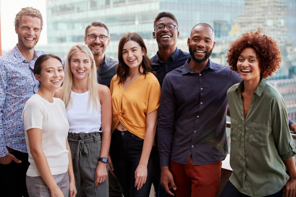 Group portrait of a creative business team standing outdoors, three quarter length, close up Group portrait of a creative business team standing outdoors, three quarter length, close up millennial generation stock pictures, royalty-free photos & images