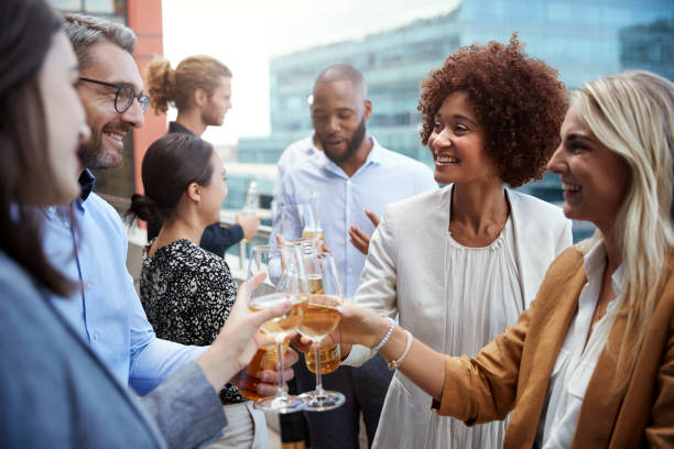 Socialising office colleagues raising glasses and making a toast with drinks after work Socialising office colleagues raising glasses and making a toast with drinks after work building terrace photos stock pictures, royalty-free photos & images