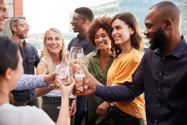 Creative business colleagues raising glasses and making a toast with drinks after work Creative business colleagues raising glasses and making a toast with drinks after work woman drinking beer stock pictures, royalty-free photos & images