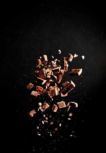 explosão do alimento do chocolate com pó de cacau, microplaquetas de chocolate e porcas - high speed flash - fotografias e filmes do acervo