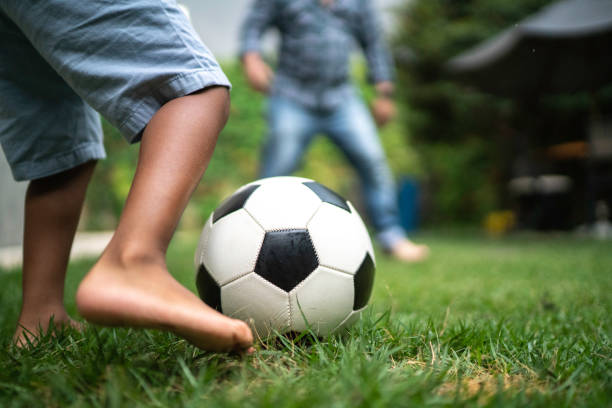 Father and son playing soccer in backyard Father and son playing soccer in backyard soccer soccer ball kicking adult stock pictures, royalty-free photos & images
